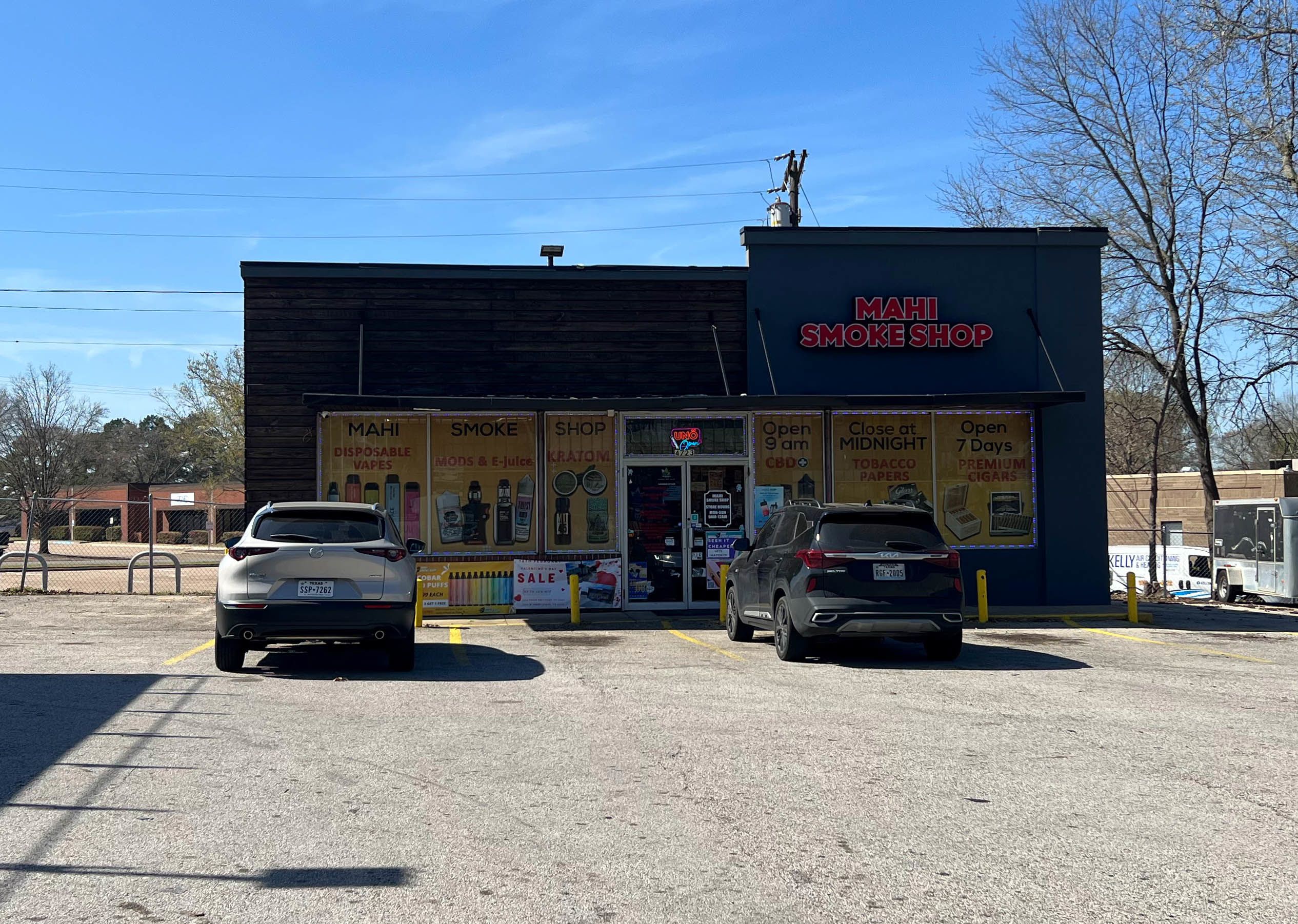 The exterior of the Mahi Food Mart is seen, two cars parked in front of it.